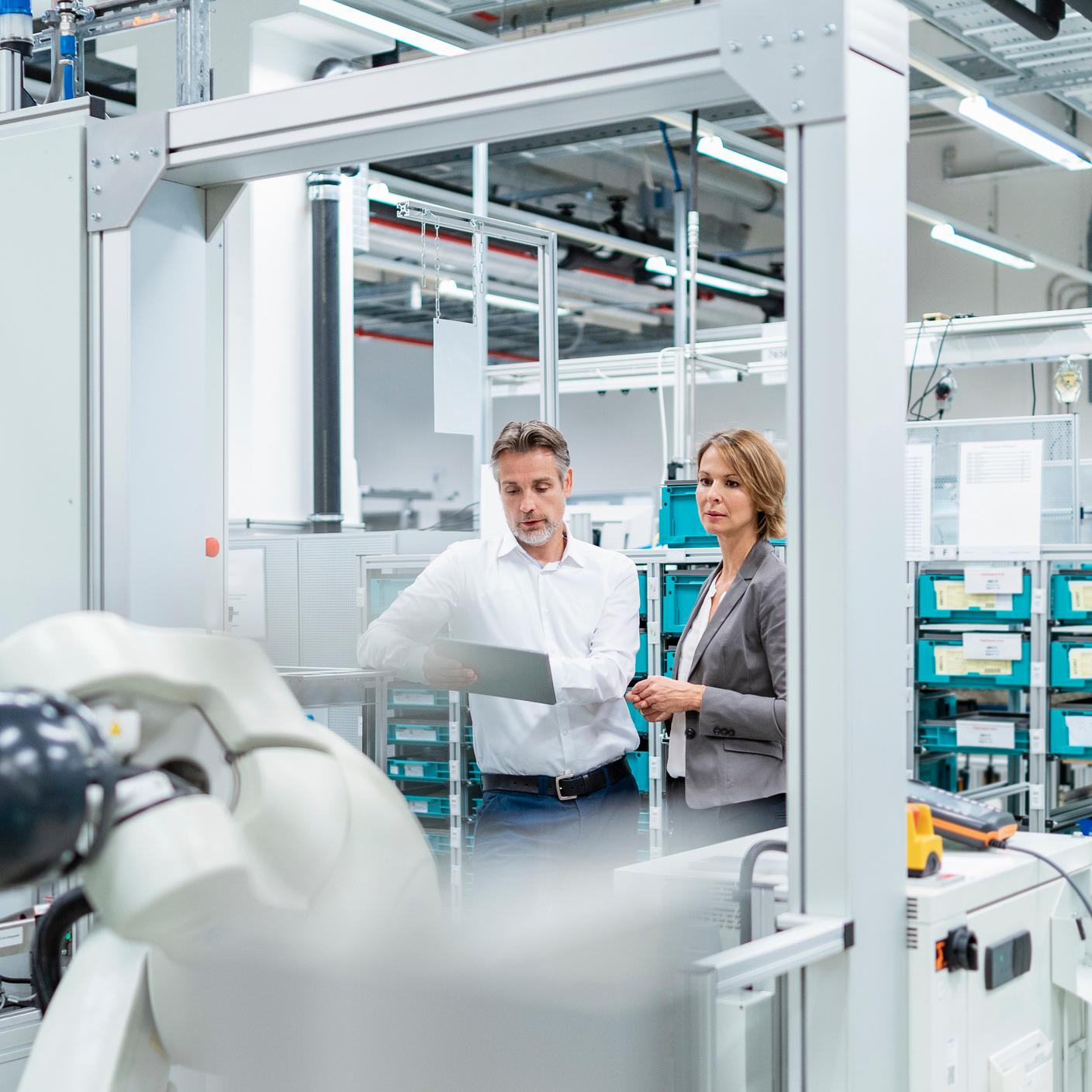 Aider l’industrie manufacturière britannique à adopter la numérisation - Une femme d’affaires et un homme muni d’une tablette discutent dans une usine moderne