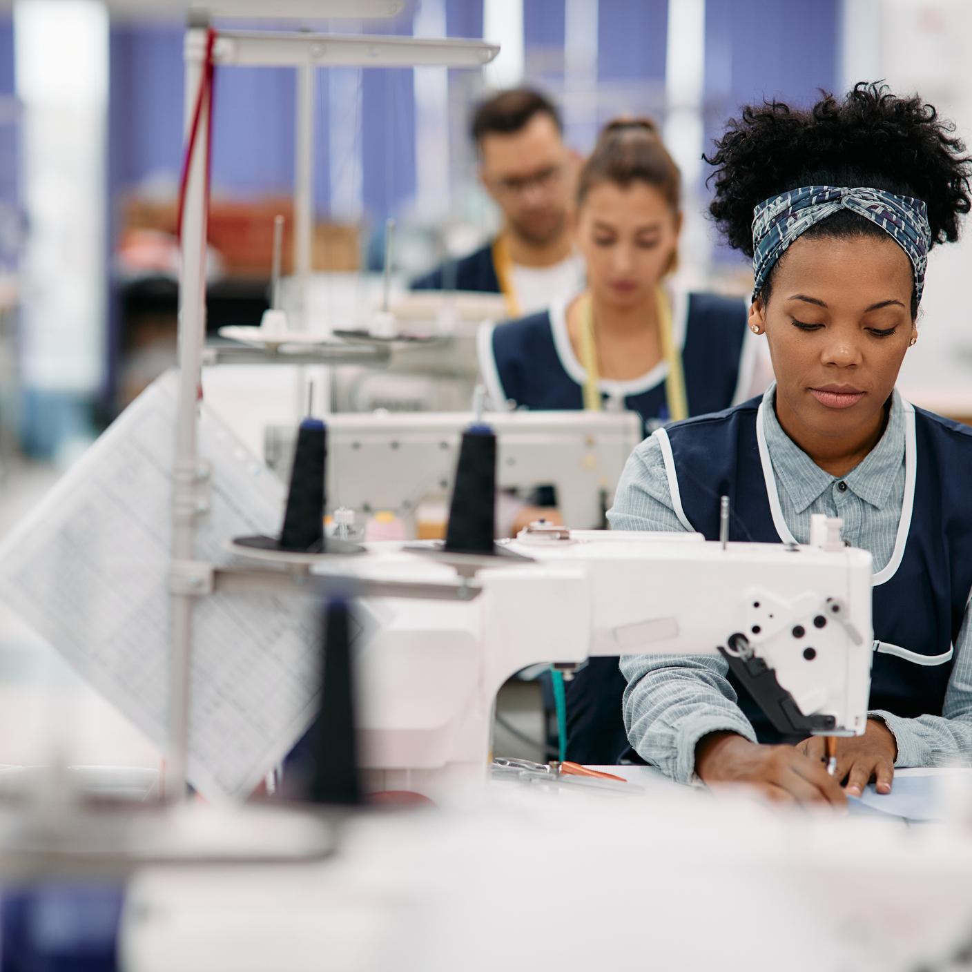 Woman sewing while working as seamstress at clothing factory.