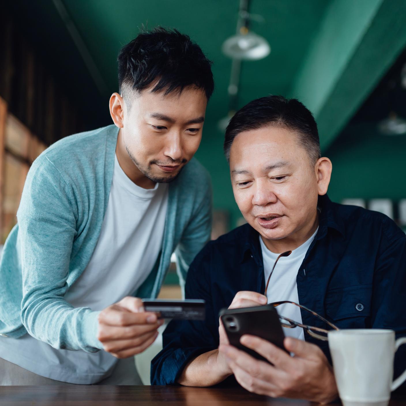 Image of Joyful Asian shopping online with mobile app on smartphone together 