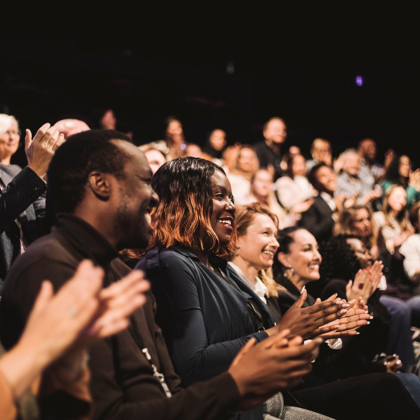 Smiling business colleagues applauding during conference event at convention centre..