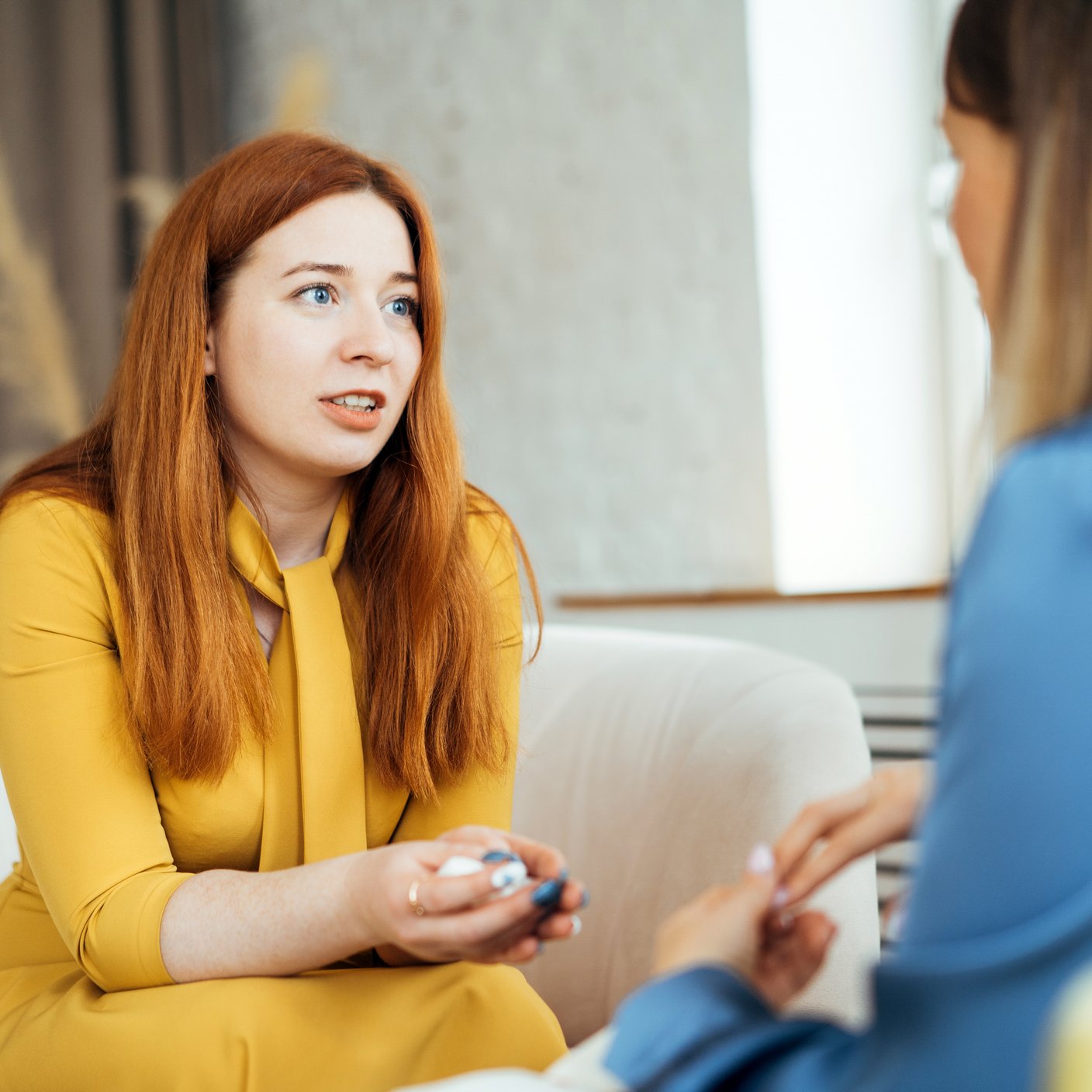 Two women in armchairs are sitting and talking