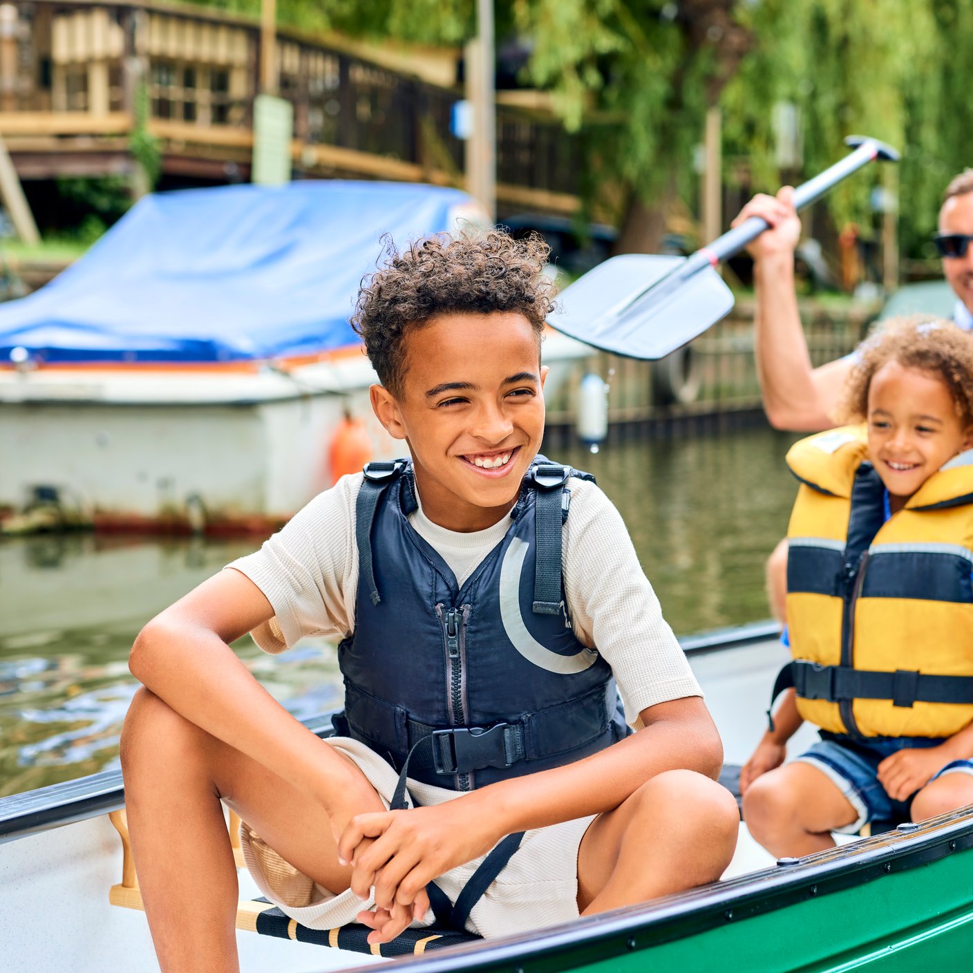Father with two sone rowing in canoe along river.
