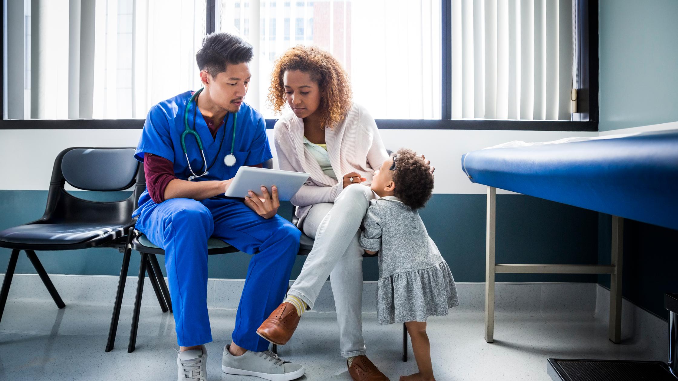 Doctor showing data on a tablet to mother and daughter