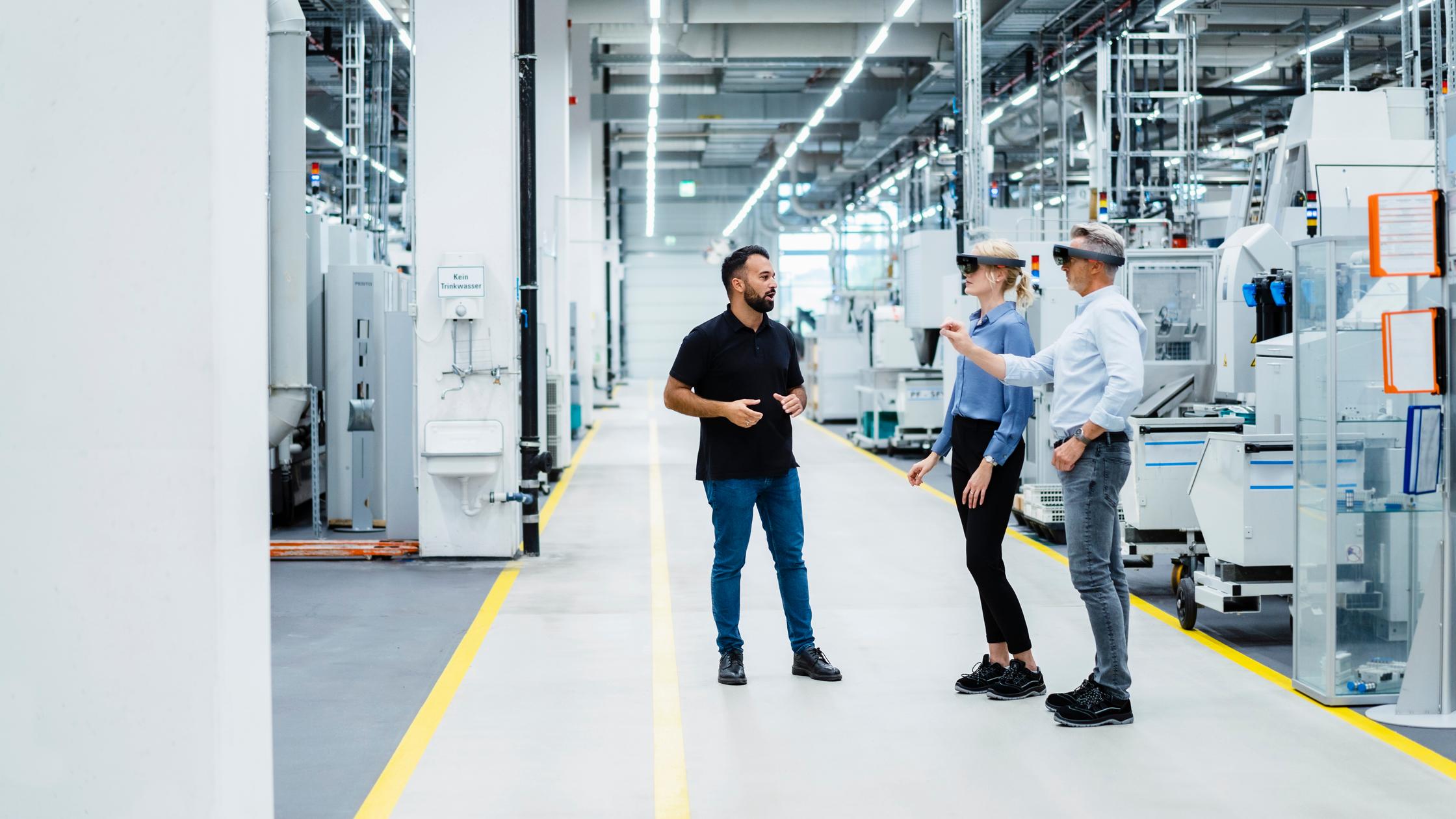 Engineer discussing with businessman and businesswoman using augmented reality glasses in industry