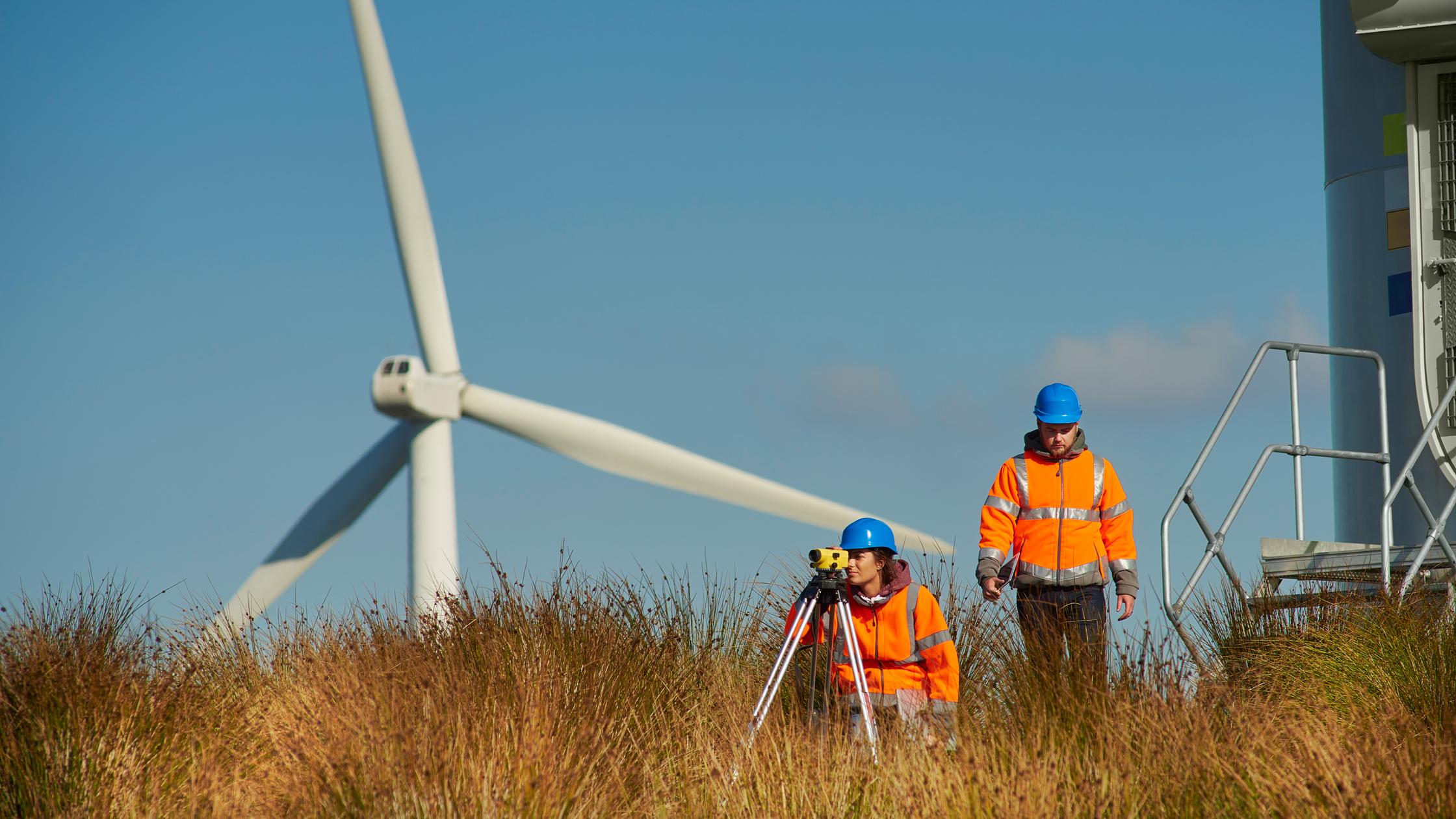 Two wind farm engineers leaving the control panel of a wind turbine.