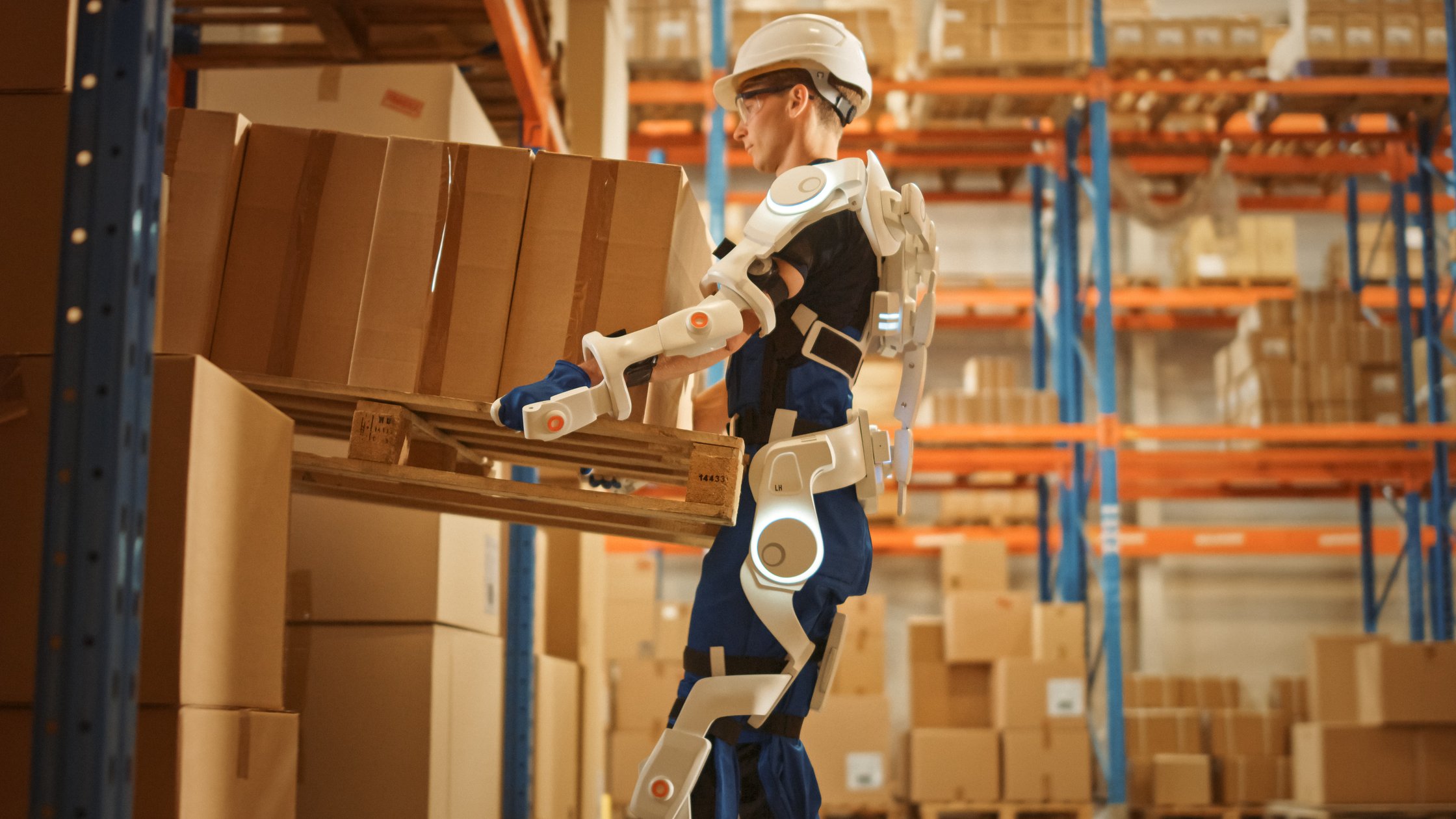 Arbeiter, der ein modernes Ganzkörper-Exoskelett trägt, hebt eine schwere Palette voller Kartons