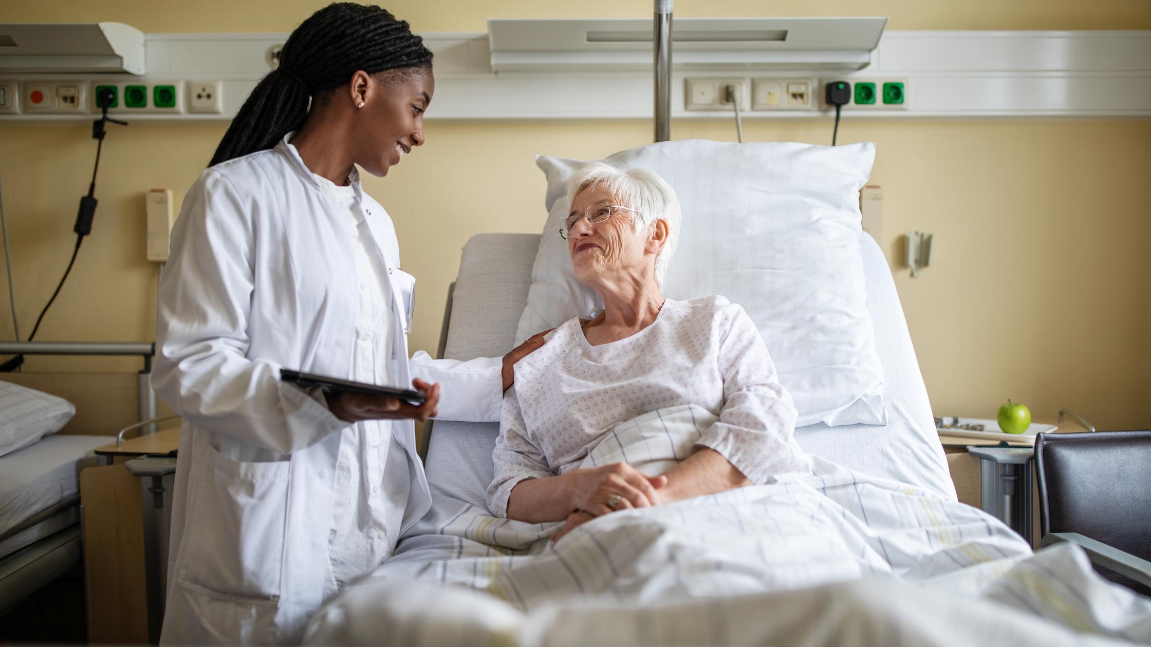 Arzt tröstet älteren Patienten während eines Besuchs auf der Station im Krankenhaus