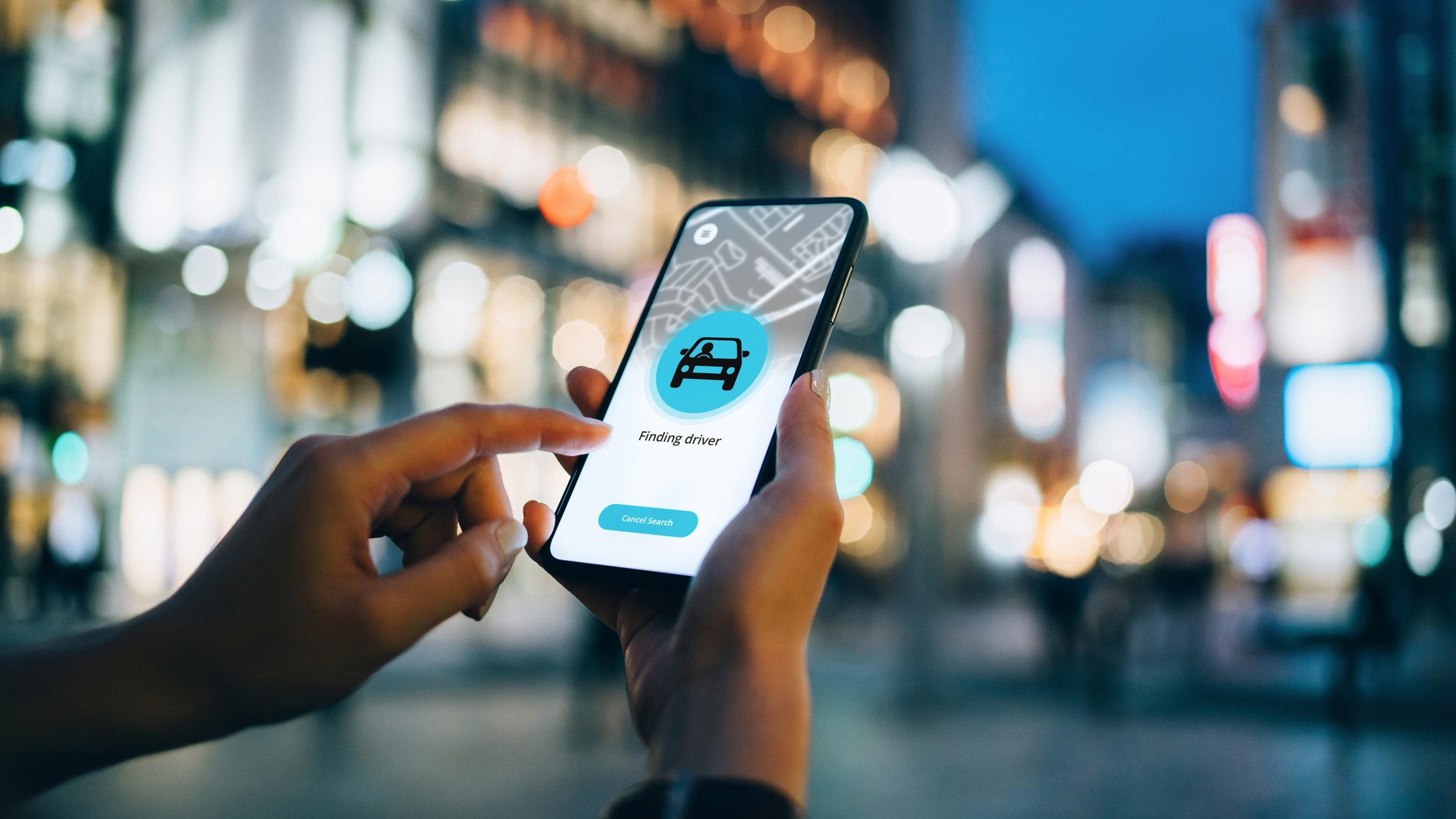 Close up of young woman using mobile app device on smartphone to arrange a taxi ride.