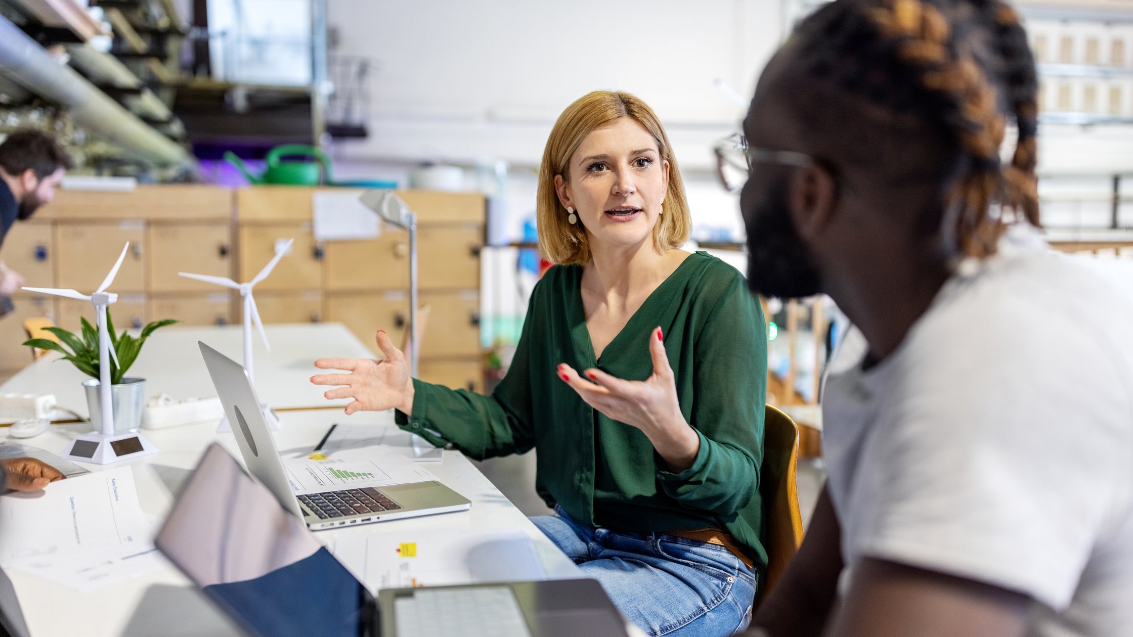 Frau, die ihrem Team während einer Besprechung in einem Startup-Büro Vorschläge macht