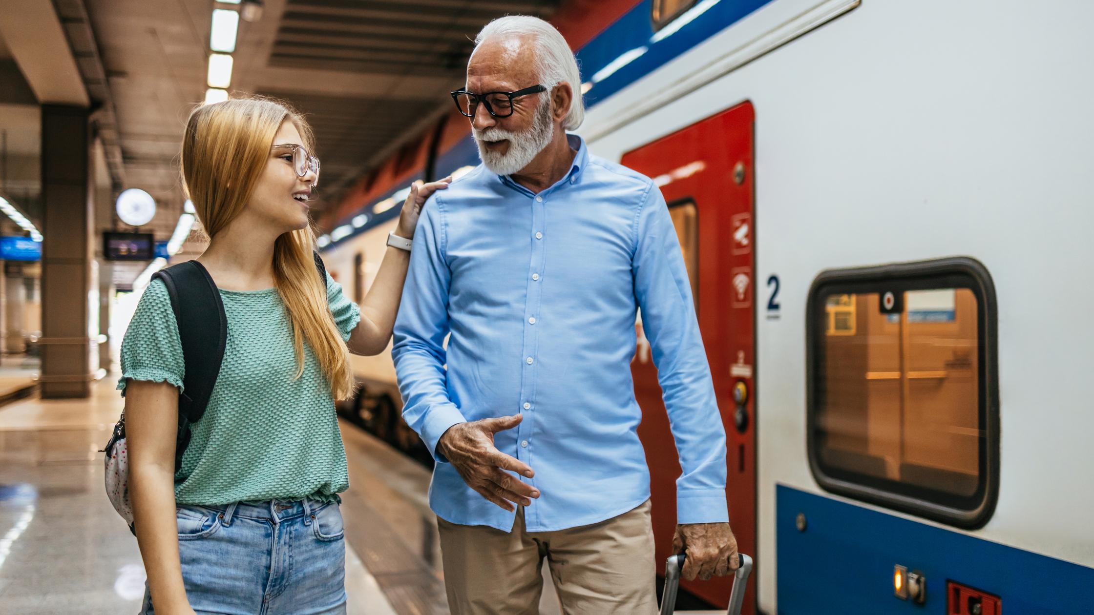 Älterer Geschäftsmann, der zusammen mit seiner Enkelin auf einen Schnellzug oder eine U-Bahn wartet